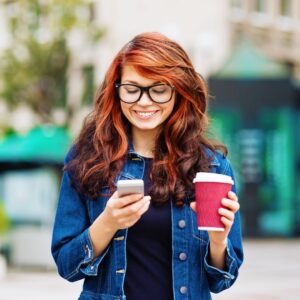 Person checking their phone while holding a coffee