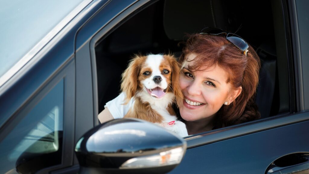 Woman and dog smiling out of a car window