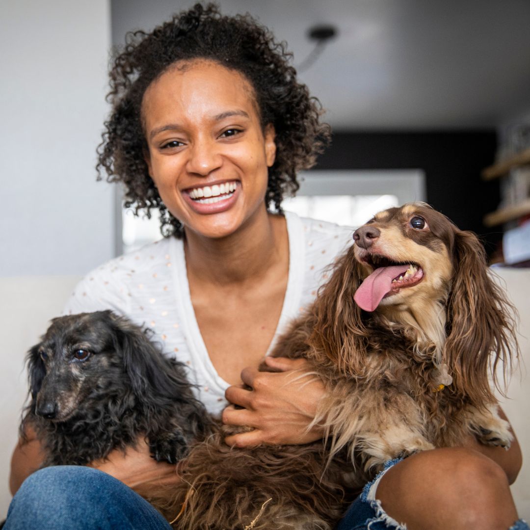 a woman happily holding two dogs in her lap