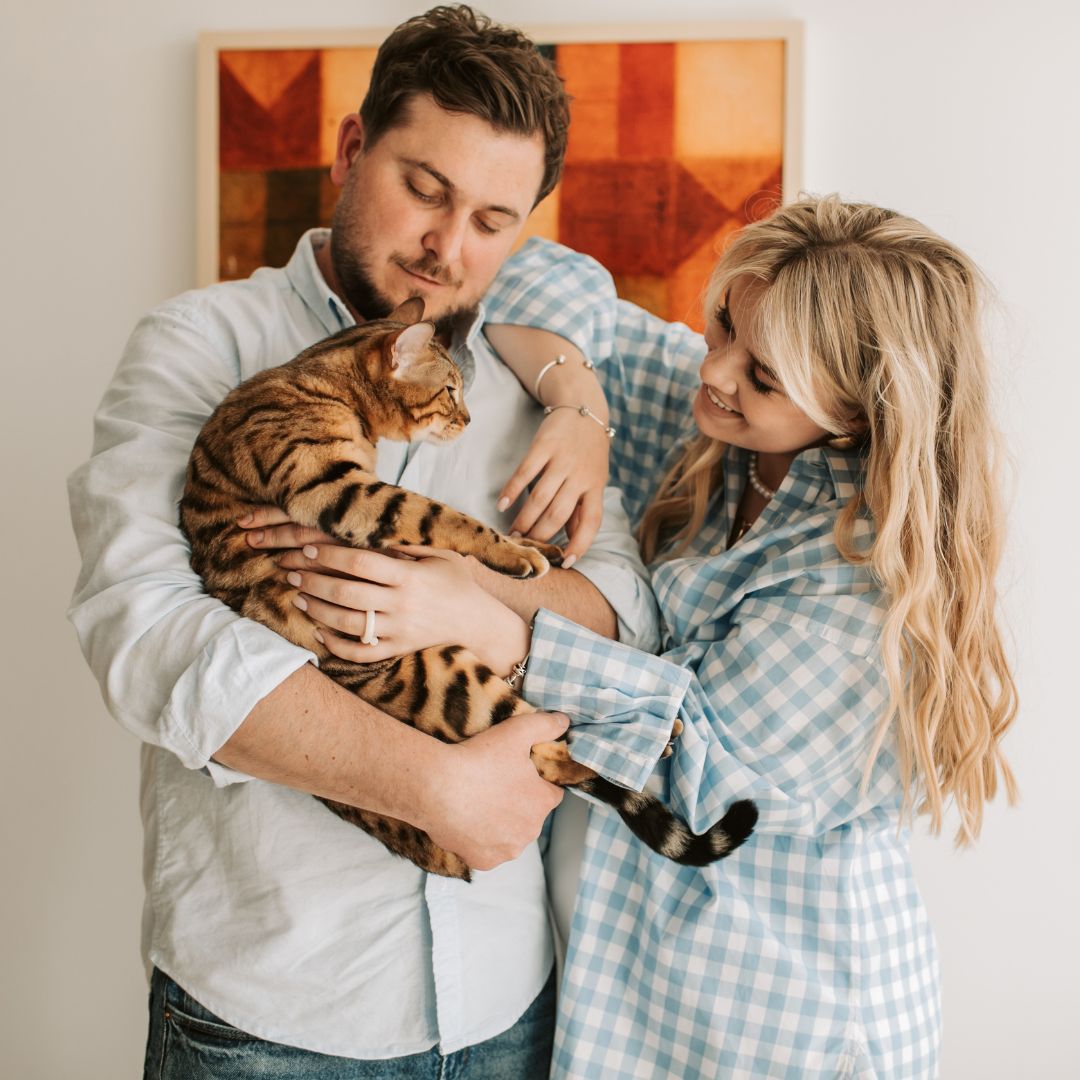a man and woman holding and petting a cat