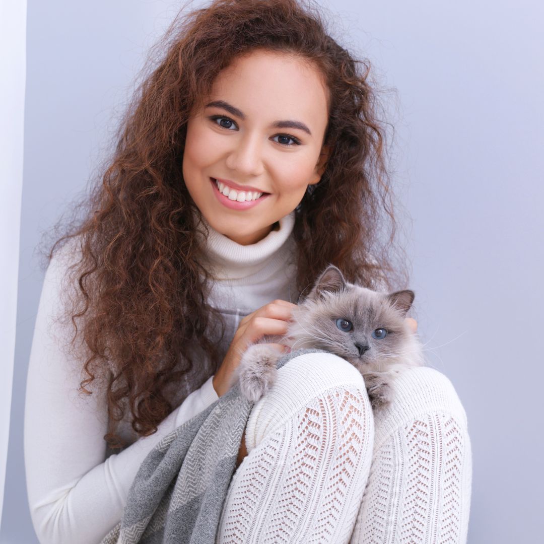 Person smiling with a cat on their lap