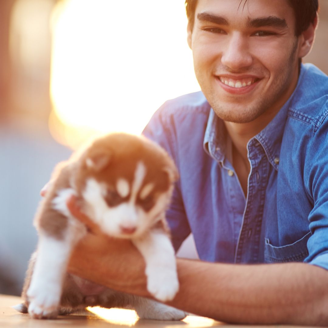 smiling man holding small puppy