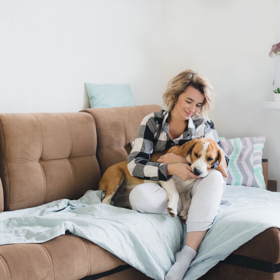 Woman cuddling with dog on the couch